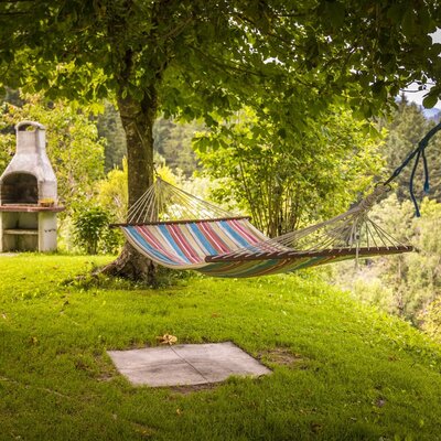 Der Garten des Bauernhofs mit Hängematte, Grill und Rasenfläche.