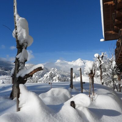 Der schneebedeckte Außenbereich des Bauernhofs bietet einen Ausblick auf die Alpen.