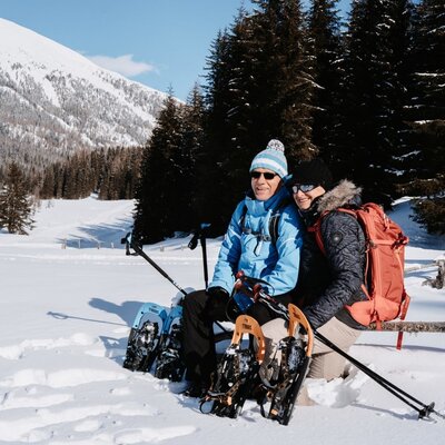 Schneeschuhwanderer in einer verschneiten Berglandschaft, die Winteraktivitäten rund um den Bauernhof darstellen.