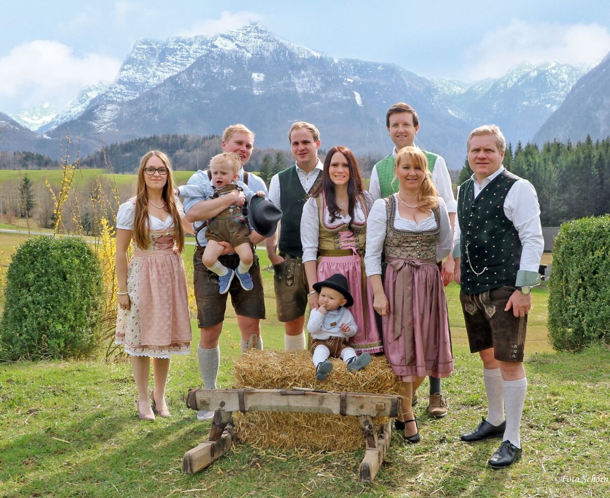 Die Gastgeberfamilie des kinderfreundlichen Bauernhofs in Tracht, umgeben von alpiner Landschaft.