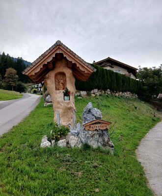 Traditioneller Bildstock mit Holzdach und einer Figur, der den Weg zum Bed and Breakfast Burnstein weist.