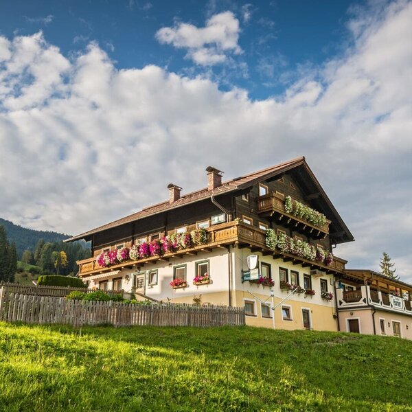 Außenansicht des Bed and Breakfast auf einem grünen Hügel mit Balkonen, die mit Blumen geschmückt sind.