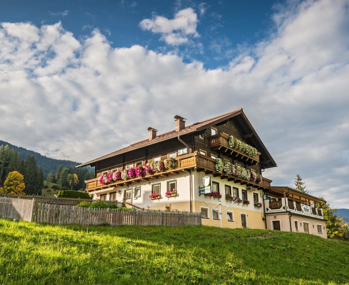 Außenansicht des Bed and Breakfast auf einem grünen Hügel mit Balkonen, die mit Blumen geschmückt sind.