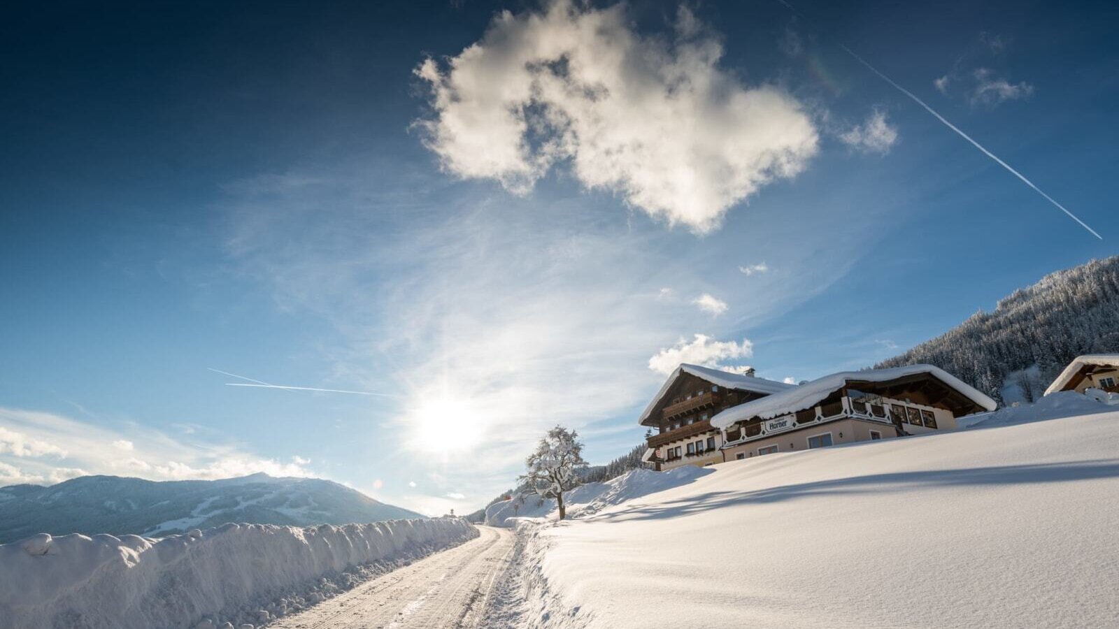 Das Bed and Breakfast in einer winterlichen Berglandschaft, mit schneebedeckten Dächern und einer Zufahrtsstraße.