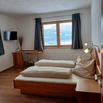 Doppelzimmer im Bed and Breakfast mit Holzbett, Schreibtisch, Fernseher und Fensterblick auf die Landschaft.