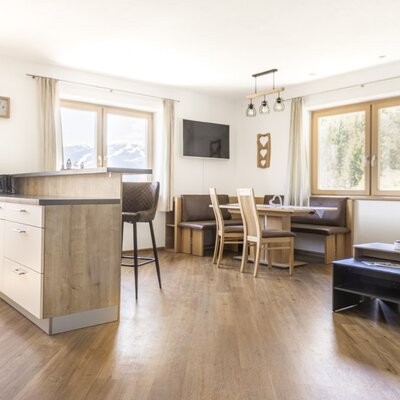 Der offene Wohnbereich im Appartement verfügt über eine voll ausgestattete Küche, einen Essbereich und einen gemütlichen Sitzbereich mit Bergblick.