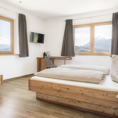 Schlafzimmer mit einem Doppelbett, einem Einzelbett, einem Schreibtisch und Bergblick.