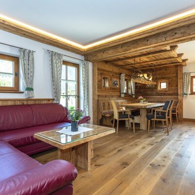 Wohn- und Essbereich im Bed and Breakfast mit rotem Ecksofa, Holztisch und Essgruppe.