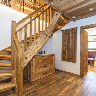Holztreppe mit einer Holzkommode darunter und einem Durchgang zu einem weiteren Raum im Bed and Breakfast.