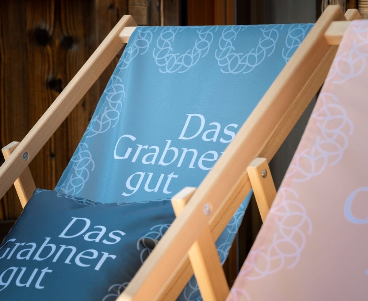 Liegestühle mit dem Logo des Bed and Breakfasts, 'Das Grabner gut'.