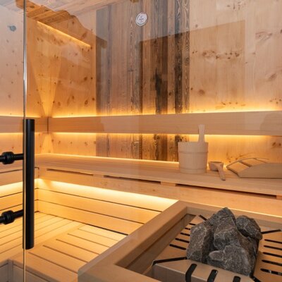 Sauna im Bed and Breakfast mit Holzbänken, Saunaofen und indirekter Beleuchtung.