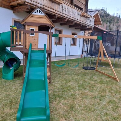 Der Kinderspielplatz des Bed and Breakfast mit Rutsche, Tunnelrutsche, Schaukeln und Trampolin.