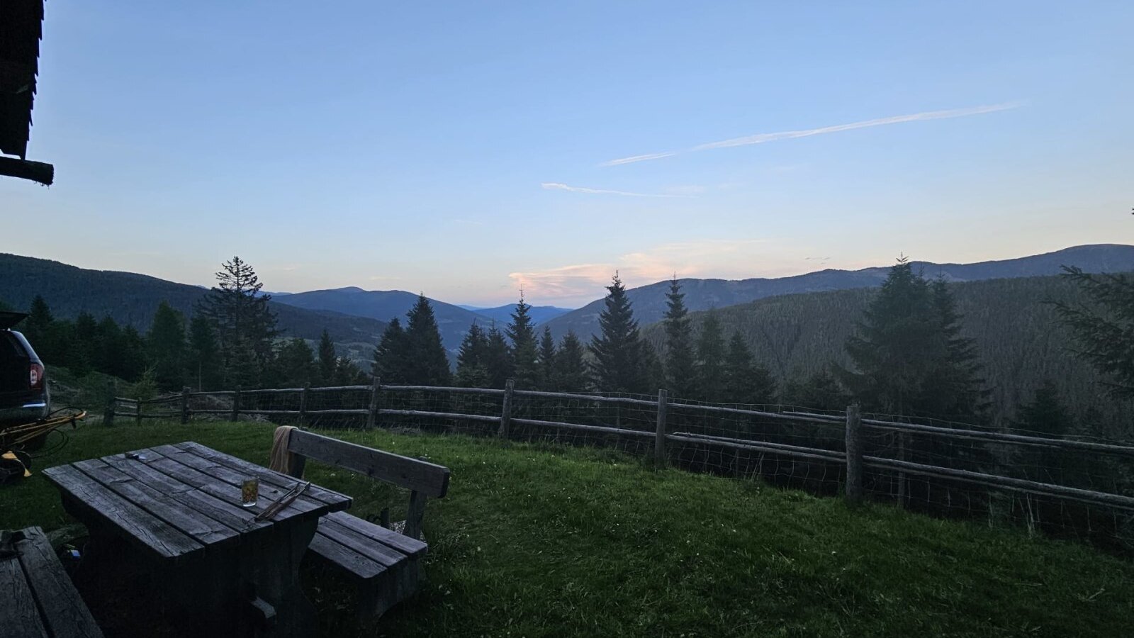 Außenbereich des Bed and Breakfast mit Holztisch, Bänken und Blick auf die Berge und Wälder.