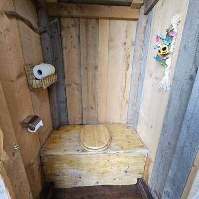 Außentoilette des Bed and Breakfast aus Holz mit Toilettenpapierhalter.