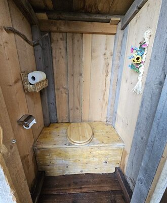 Außentoilette des Bed and Breakfast aus Holz mit Toilettenpapierhalter.