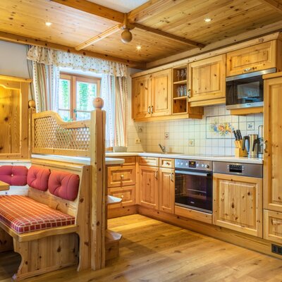 Die helle Wohnküche des Bauernhofs ist mit Vollholzmöbeln, einer Sitzecke sowie Backofen, Mikrowellenherd und Geschirrspüler ausgestattet.
