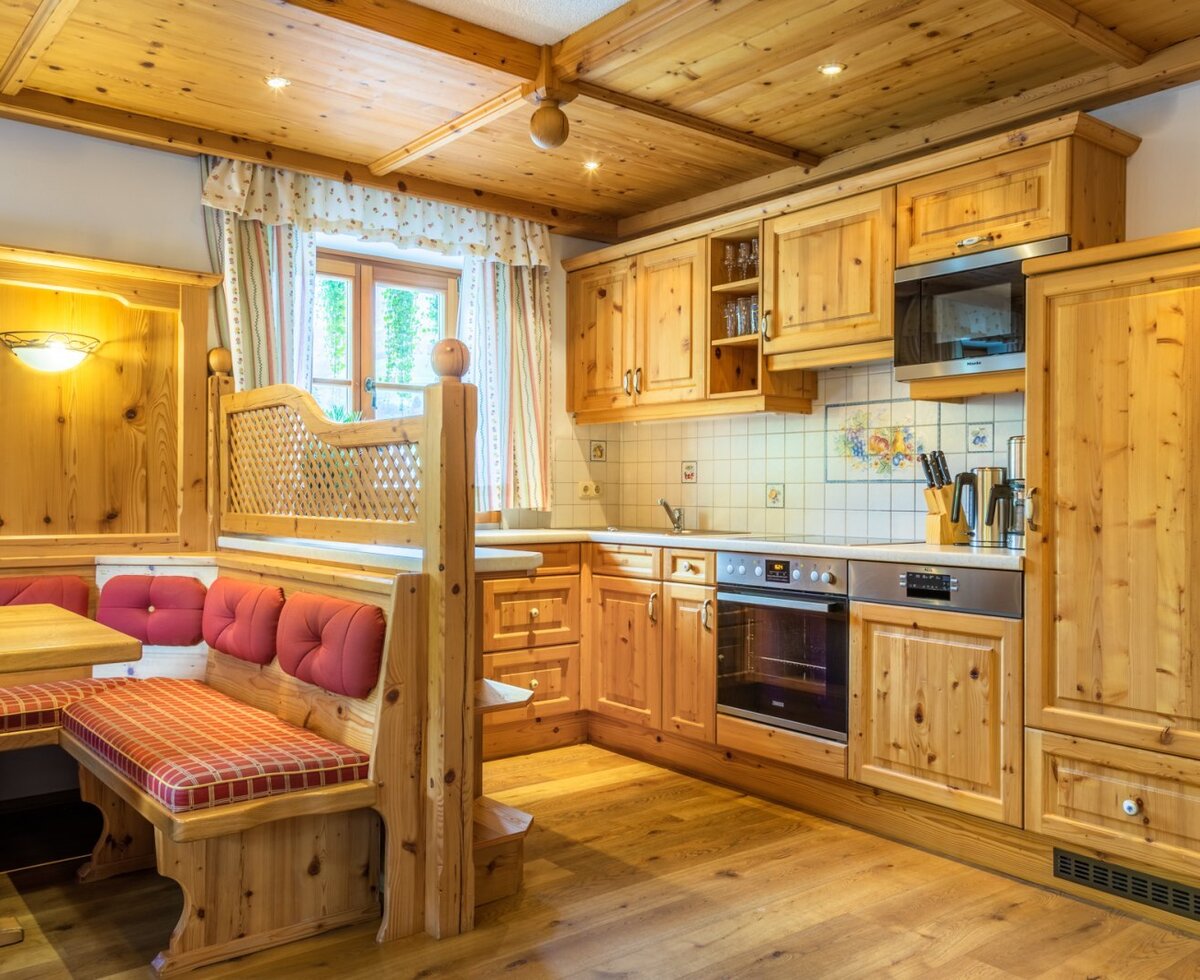 Die helle Wohnküche des Bauernhofs ist mit Vollholzmöbeln, einer Sitzecke sowie Backofen, Mikrowellenherd und Geschirrspüler ausgestattet.