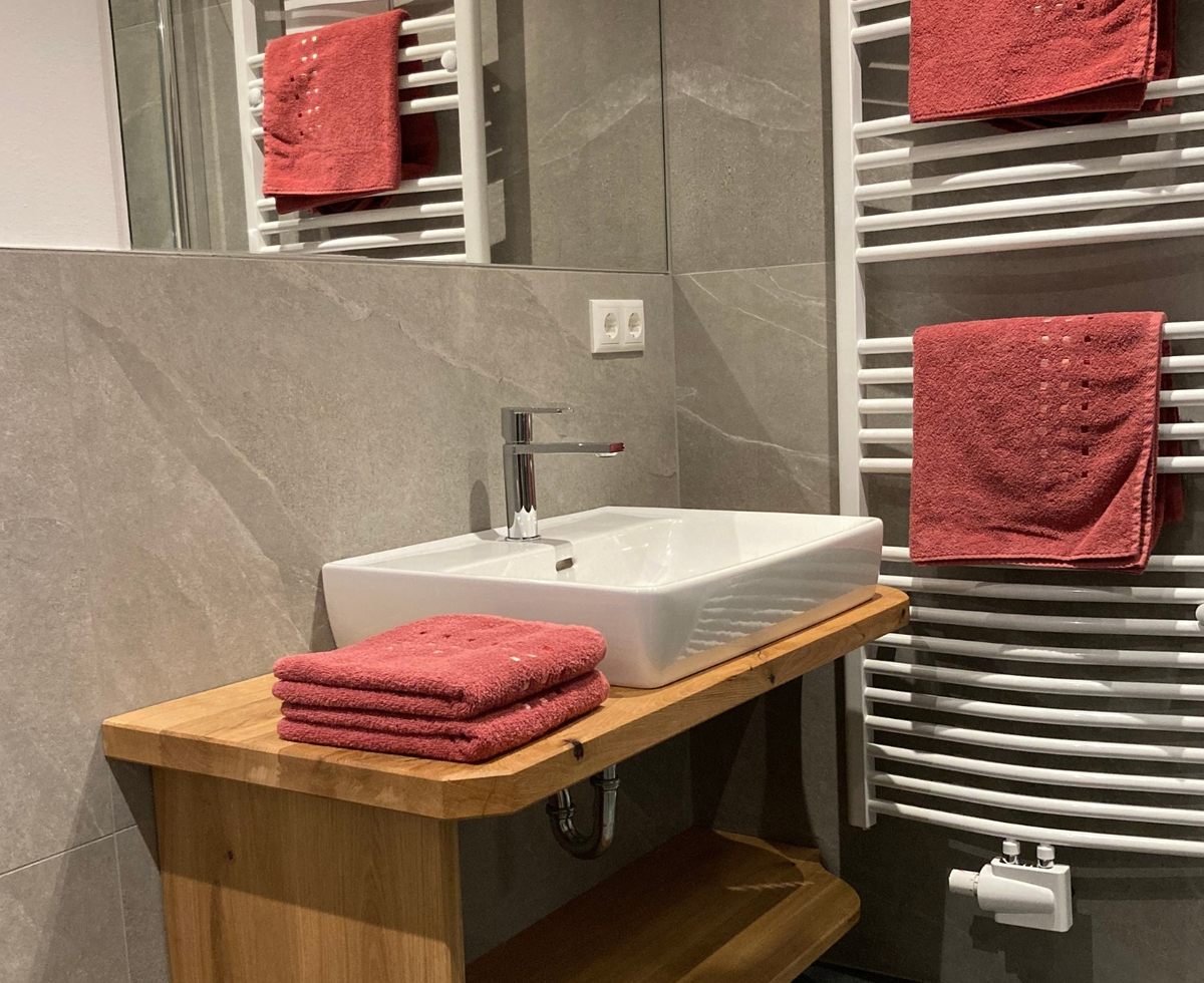 Modernes Badezimmer der Alm mit Waschbecken, Holzunterschrank und Handtuchheizkörper.