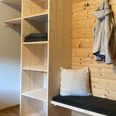 Gardarobe mit Holzregalen, einer Sitzbank und Garderobenhaken.