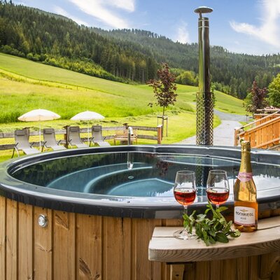 Der einladende, holzbeheizte Hot Pot der Almhütte mit herrlichem Blick auf die umliegenden grünen Wiesen und Wälder.