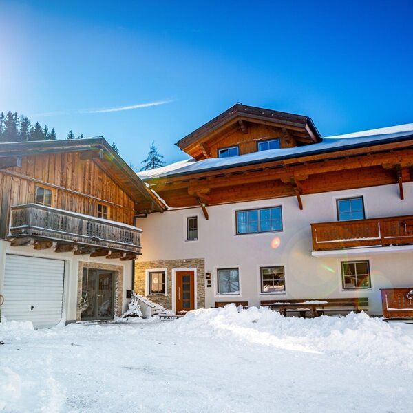 Der Bauernhof im Winter mit verschneiten Balkonen und Zugang zum Skikeller.