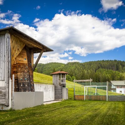Außenbereich des Bauernhofs mit einer Kletterwand und einem umzäunten Fußballplatz.