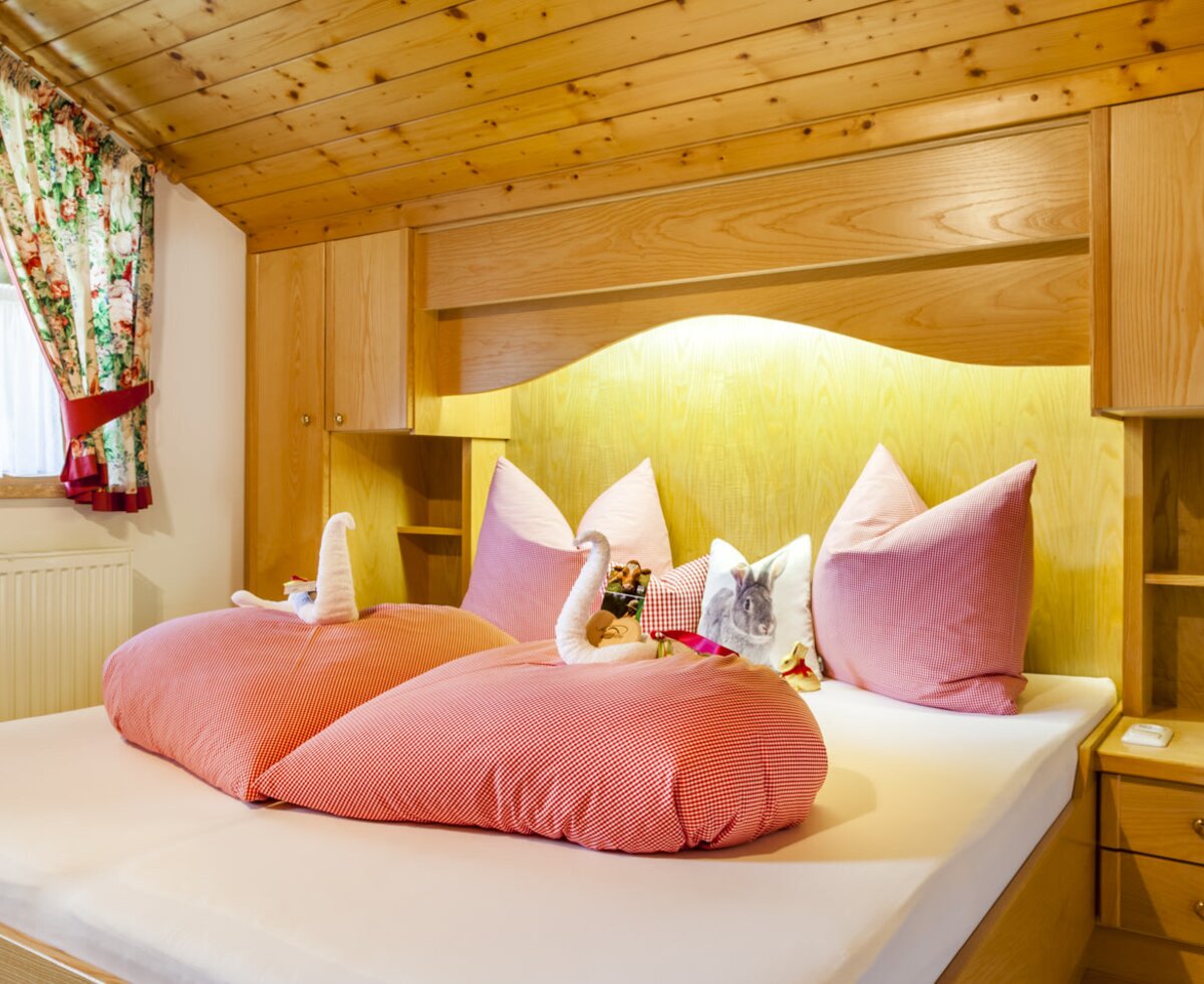 Doppelbett in einem der Schlafzimmer des Bauernhofs mit Holzeinrichtung, integriertem Stauraum und Fenster.