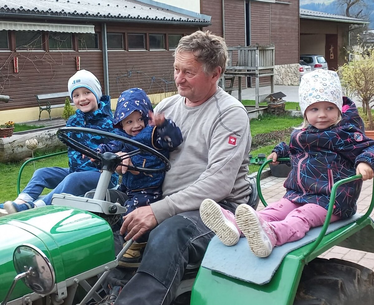 Traktorfahrt mit Kindern und einem Erwachsenen auf dem Bauernhof.