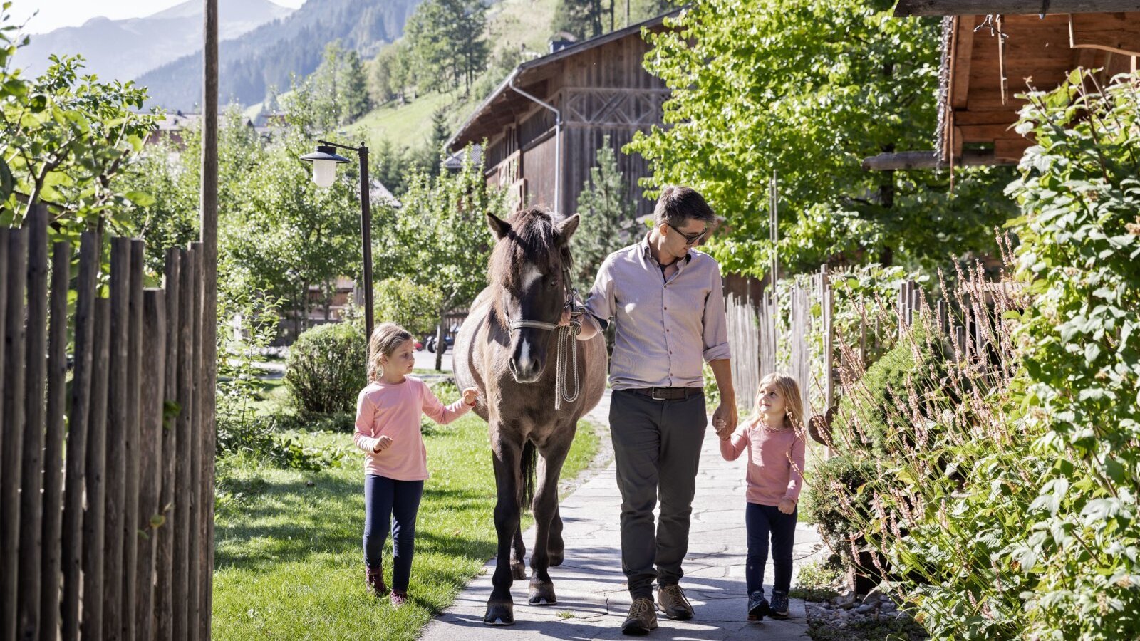 Kinder und ein Erwachsener beim Umgang mit einem Pferd auf dem Bauernhof.