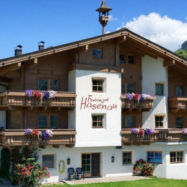 Feriengut Hasenau mit traditioneller Holzarchitektur, blumengeschmückten Balkonen und Bergblick.