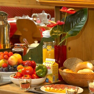 Frühstücksbuffet mit frischem Obst, Gemüse, Brot, Aufschnitt und Getränken.