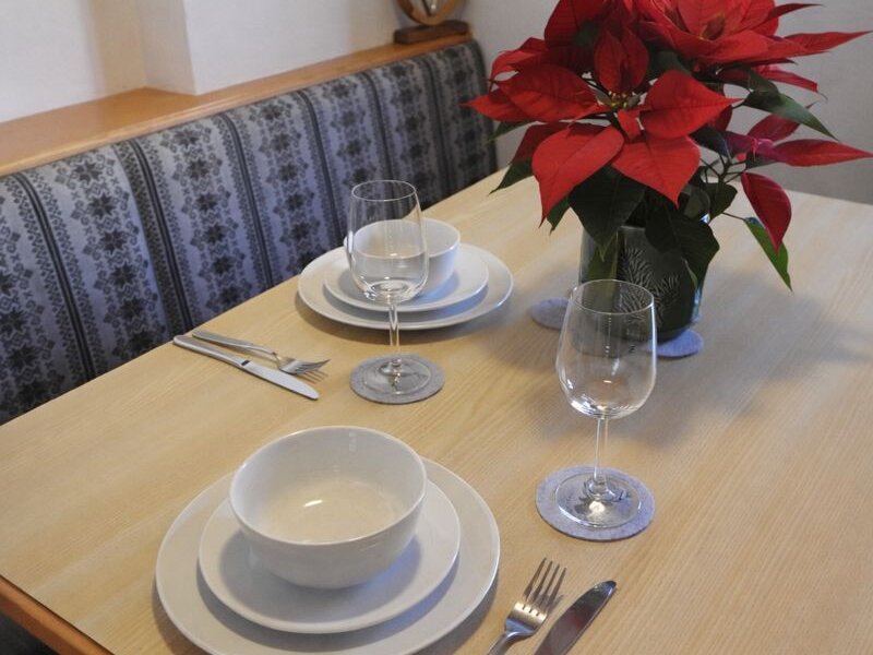 Der Esstisch ist für zwei Personen gedeckt und mit einem Weihnachtsstern dekoriert.