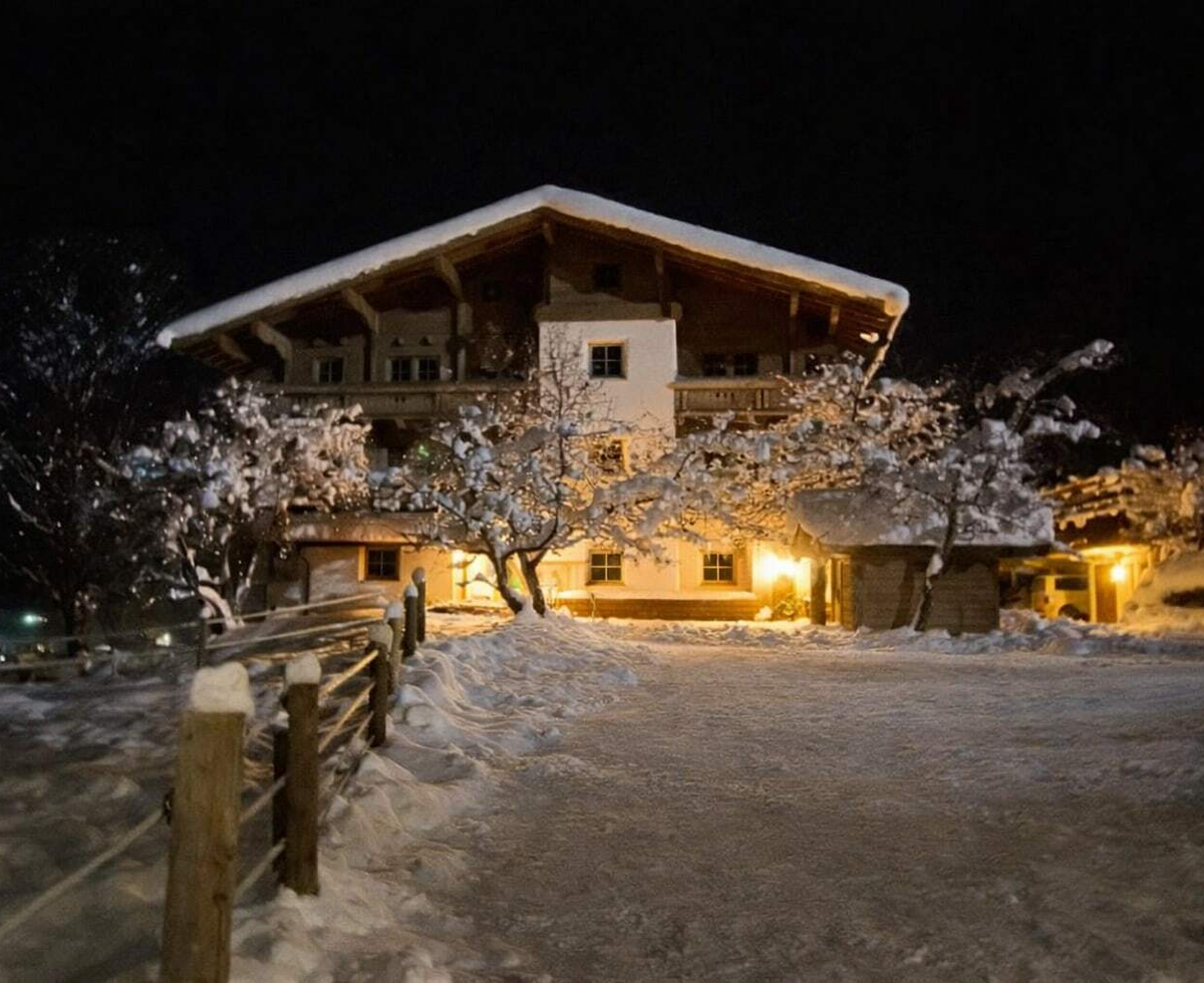 Außenansicht bei Nacht, mit Schnee bedeckt und beleuchteten Fenstern.