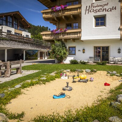 Der einladende Außenbereich des Bauernhofs mit einem Sandkasten für Kinder und einer gemütlichen hölzernen Sitzecke.