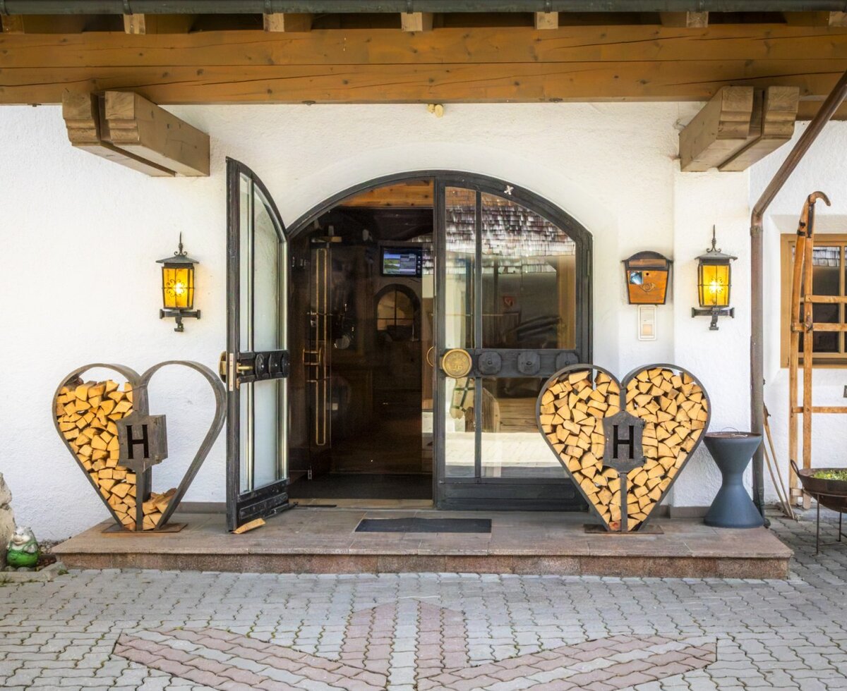 Der einladende Eingangsbereich des Bauernhofs mit herzförmigen Holzstapeln, warmen Wandlaternen und traditionellem Charme.