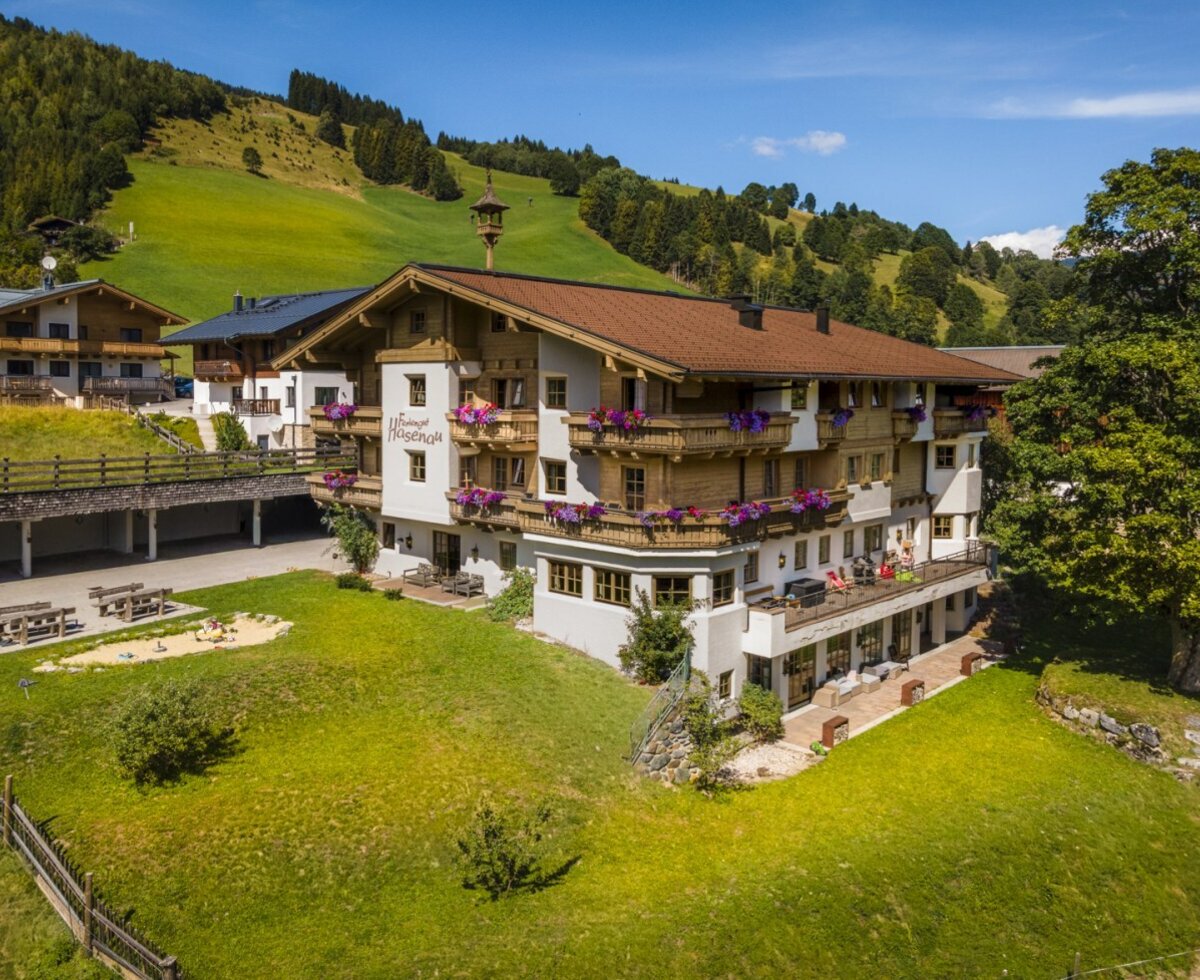Der einladende Bauernhof inmitten grüner Wiesen mit blumengeschmückten Balkonen und einem weitläufigen Garten.