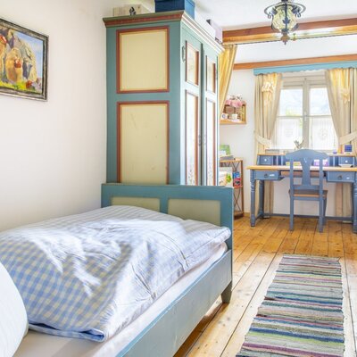 Einzelzimmer im Ferienhaus mit Einzelbett, Kleiderschrank, Schreibtisch und Fenster.