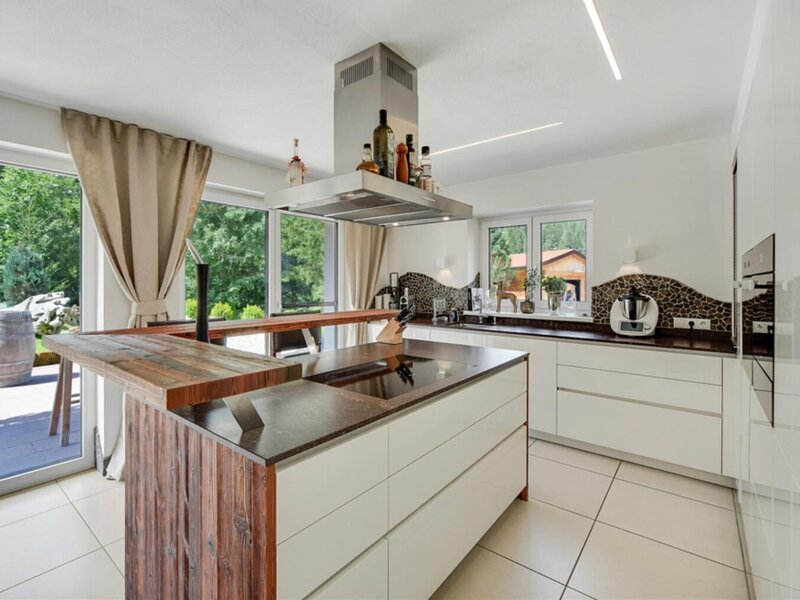Moderne Küche der Ferienwohnung mit Kochinsel, integriertem Kochfeld, Frühstückstheke und direktem Zugang zur Terrasse.