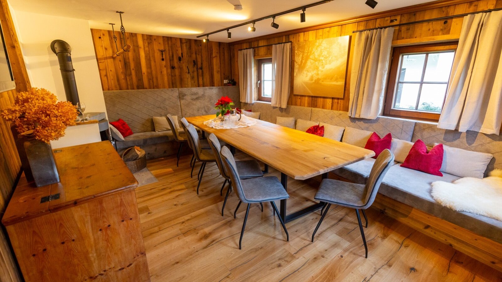 Essbereich im Bed and Breakfast mit langem Holztisch, Sitzbänken, Holzofen und Holzwänden.