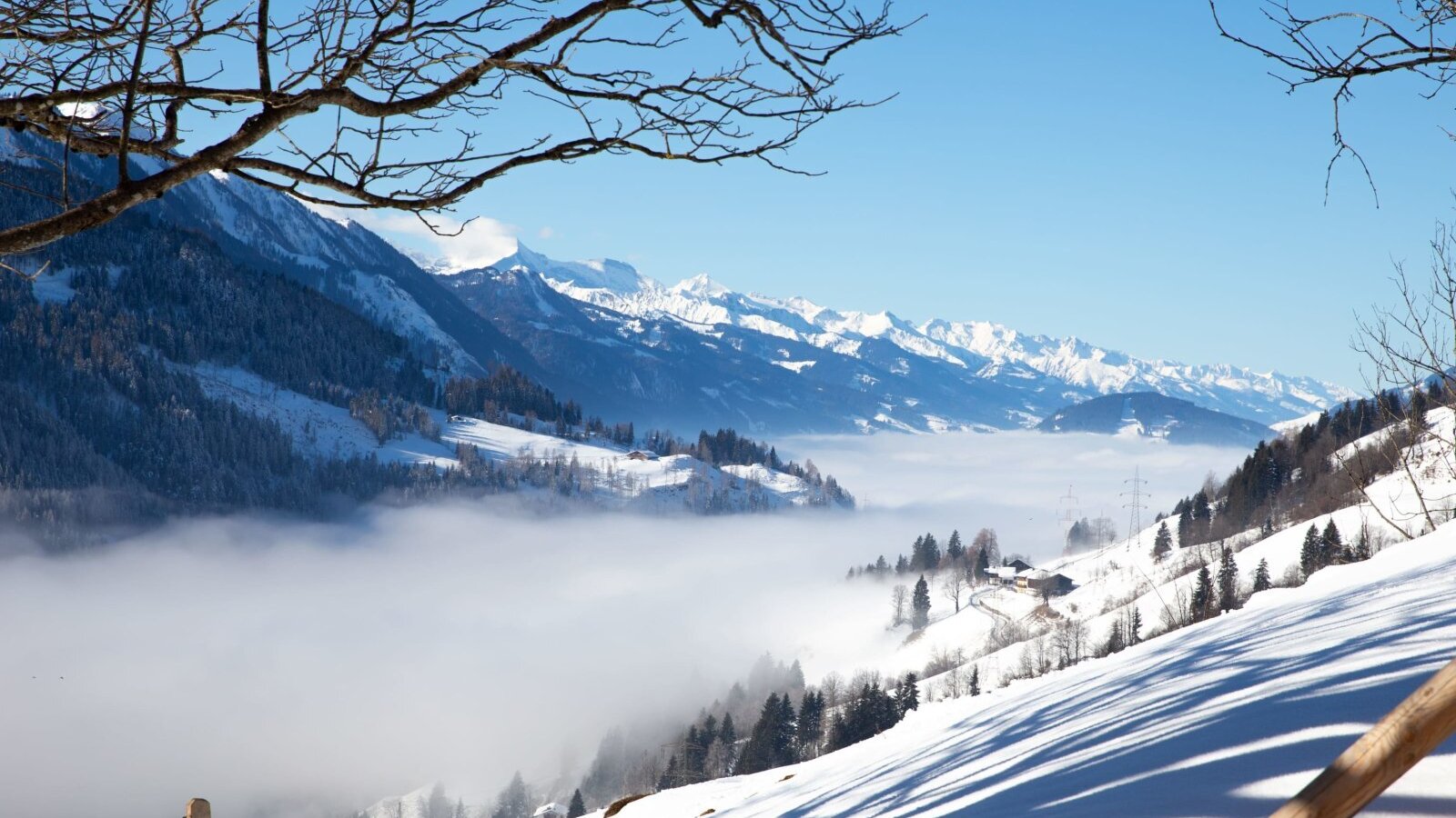 Blick auf die winterliche Berglandschaft mit Talnebel und schneebedeckten Gipfeln.