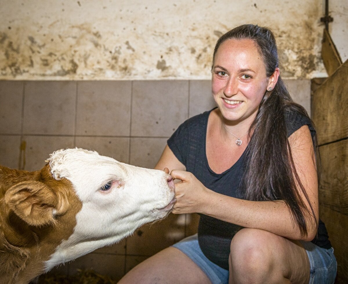 Eine Frau füttert ein Kalb auf dem Bauernhof.