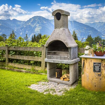 Die Alm bietet einen Steingrill mit Brennholz und einem Beistelltisch auf dem Rasen mit Bergblick.