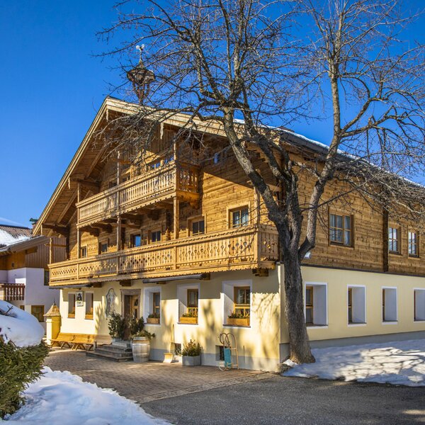 Der Bauernhof im Winter, mit traditioneller Holzfassade und geschnitzten Balkonen.