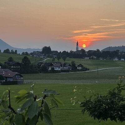 Ein idyllischer Ausblick vom Bauernhof auf den stimmungsvollen Sonnenuntergang über dem malerischen Dorf.