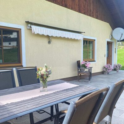 Die einladende Terrasse des Bauernhofs mit einer gemütlichen Sitzecke und hübschem Blumenschmuck.