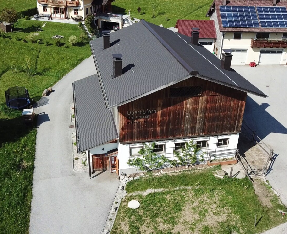 Vogelperspektive auf den traditionellen Bauernhof, umgeben von saftig grünen Wiesen.