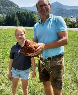 Herzliche Momente mit den Tieren auf dem Bauernhof vor einer malerischen Bergkulisse.