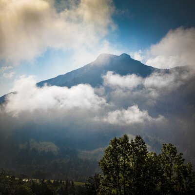 Blick auf die umliegende Berglandschaft und Wolkenformationen vom Bauernhof.