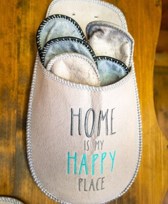 Pantoffeln für Gäste, präsentiert in einem Filzhalter mit der Aufschrift „HOME IS MY HAPPY PLACE“ im Bauernhof.