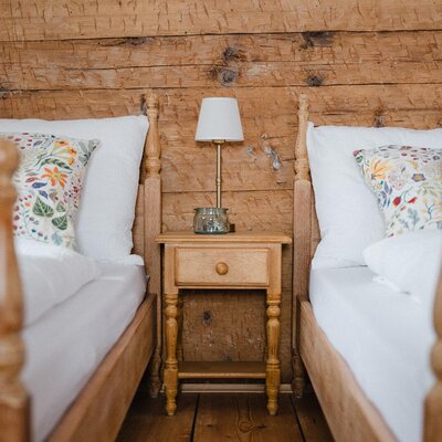 Schlafzimmer im Bed and Breakfast mit zwei Einzelbetten, Holzwand und Nachttisch mit Lampe.